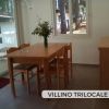 Sala da pranzo con tavolo e sedie in legno, finestre luminose.