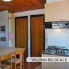 Cucina con tavolo e sedie, due porte chiuse dietro.