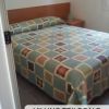 Camera con letto matrimoniale e copriletto multicolore.
