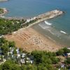 Spiaggia affollata con ombrelloni vicino a una scogliera.