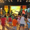 Bambini ballano davanti a un palco con animatori.