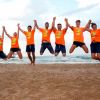 Persone in maglie arancioni saltano sulla spiaggia.