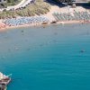 Spiaggia con ombrelloni colorati e mare calmo.