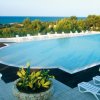 Piscina con lettini bianchi e vista sul mare.