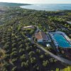 Vista aerea di un complesso con piscina e uliveti vicino al mare.