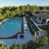 Piscina con ombrelloni e un edificio coperto accanto.