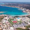 Veduta aerea di una costa con acque turchesi e strutture turistiche.