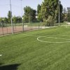 Campo da calcio con prato verde e recinzione.