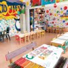 Stanza per bambini decorata con murales vivaci e tavoli colorati.