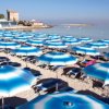Spiaggia con ombrelloni blu e mare calmo.