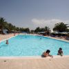 Piscina all'aperto con palme e bagnanti.