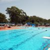 Piscina all'aperto con scivolo circondata da ombrelloni.