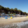 Una spiaggia con lettini e ombrelloni azzurri.