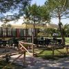 Tavoli all'aperto sotto un gazebo tra alberi.