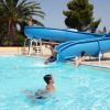 Bambini che giocano in piscina con scivolo blu.