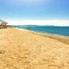 Spiaggia di sabbia con ombrelloni e mare calmo.