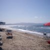 Spiaggia con ombrelloni blu e bianchi, mare calmo.