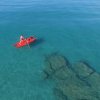 Persona su canoa rossa in acqua limpida.