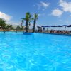 Piscina con palme e ombrelloni blu sotto un cielo soleggiato.