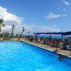 Bordo piscina con ombrelloni blu e persone che si rilassano al sole.