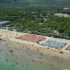 Spiaggia affollata con ombrelloni arancioni e blu.