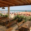 Vista di una spiaggia con ombrelloni arancioni e tavoli sotto un portico.