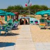 Una spiaggia con sdraio verdi e ombrelloni.