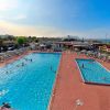 Due piscine all'aperto con lettini e persone che nuotano.