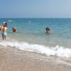 Bambini e adulti giocano in acqua vicino alla riva.