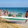 Due uomini trasportano una piccola barca sulla spiaggia.