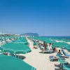Spiaggia con ombrelloni verdi e mare azzurro.