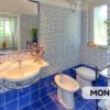 Bagno con piastrelle blu e bianche, bidet e doccia.