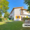 Casa bianca a due piani con giardino e sedie a sdraio.