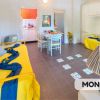 Sala luminosa con due divani gialli e tavolo.