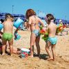 Bambini giocano sulla spiaggia con secchielli.