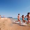 Persone corrono verso il mare su una spiaggia.