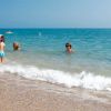 Bambini giocano tra le onde al mare.