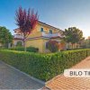 Casa gialla circondata da siepi.