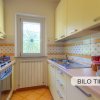 Cucina con armadietti gialli e finestra decorata.