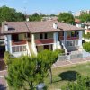 Complesso residenziale con tetti in tegole e alberi verdi.