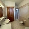 Un bagno con lavandino, doccia, bidet e WC, arredato con mattonelle beige e una porta in legno.