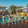 Bambini e adulti corrono lungo il bordo di una piscina durante un'attività di gruppo.