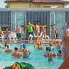 Attività di gruppo in una piscina all'aperto con molti bambini e alcuni adulti.