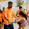Persone in t-shirt arancioni su una spiaggia.