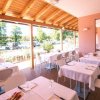 Ristorante all'aperto con tavoli apparecchiati, tetto in legno e vista su un parcheggio alberato.