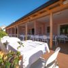 Ristorante all'aperto con tavoli apparecchiati sotto una veranda in legno.