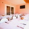 Sala da pranzo con pareti rosa, tavoli apparecchiati con tovaglie bianche e TV a schermo piatto.