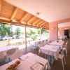Portico di ristorante con tavoli apparecchiati, soffitto in legno, vista sul parcheggio.