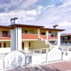 Complesso residenziale a due piani con balconi rossi e recinzione bianca.