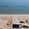 Spiaggia con ombrelloni ordinati, vista mare e piscina.